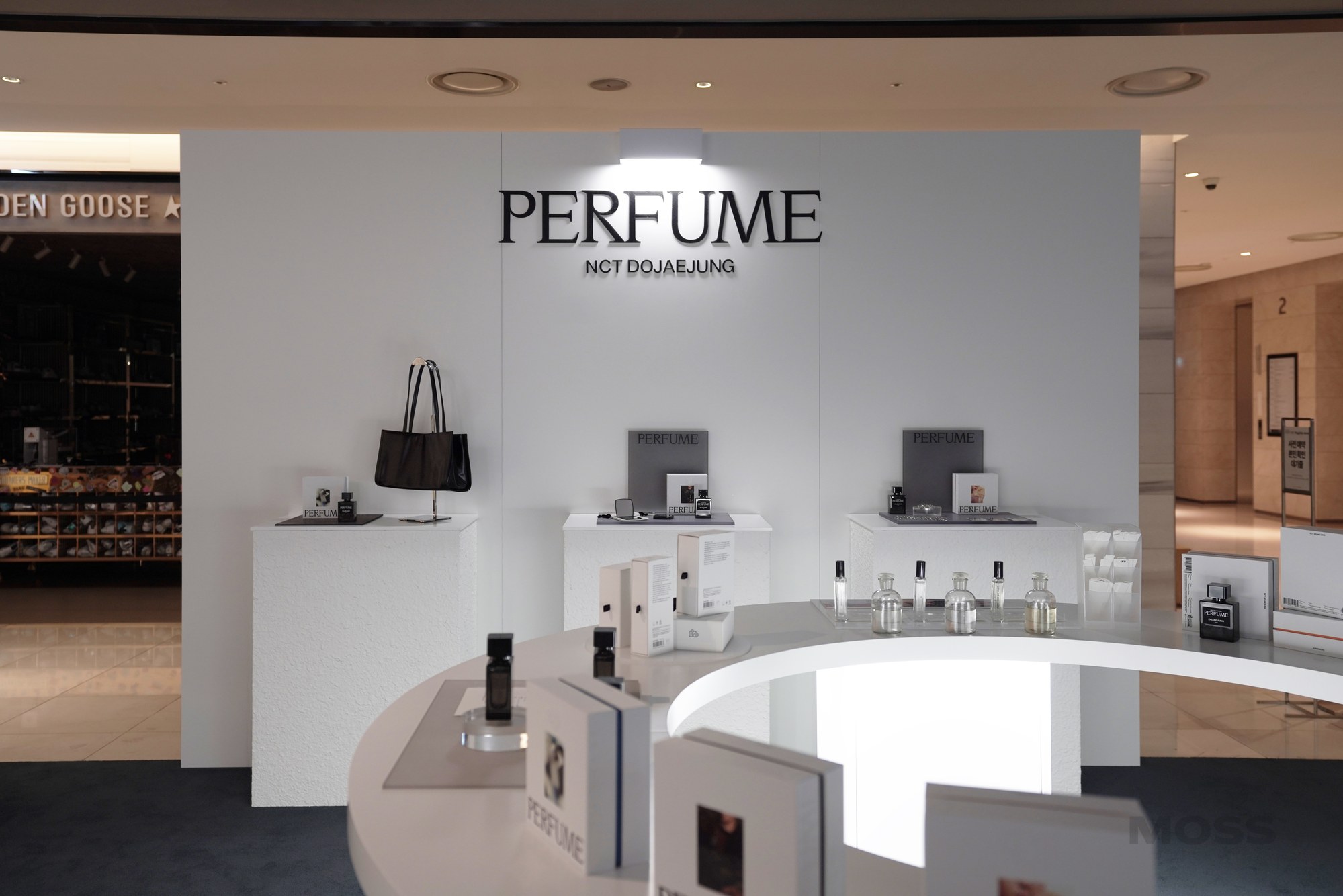 PERFUME 사인 아래 제품과 가방이 진열된 벽면